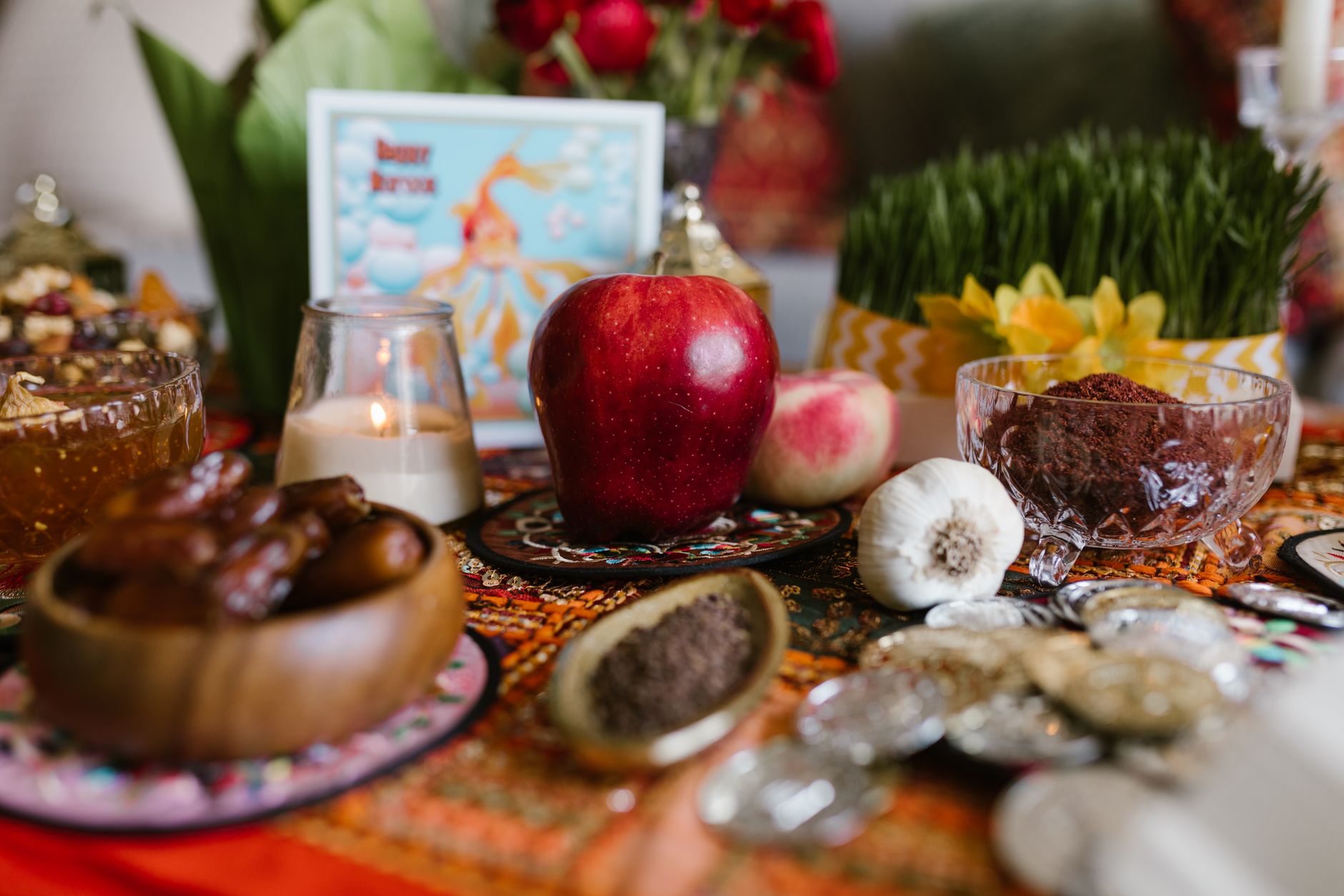 Close-up of apple slices and a jar of honey on a wooden board with pomegranate seeds nearby