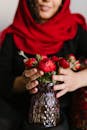 Crop Photo Of Woman Holding A Vase With Red Flowers