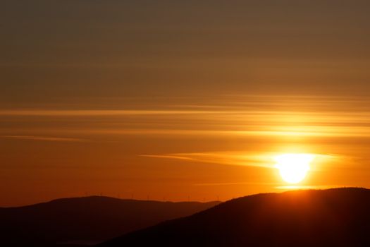 A stunning sunset view over mountains with vibrant orange hues and silhouettes.