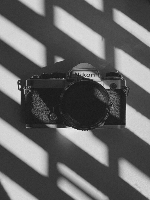 Free Black-and-white shot of a Nikon camera with dramatic light and shadows. Stock Photo