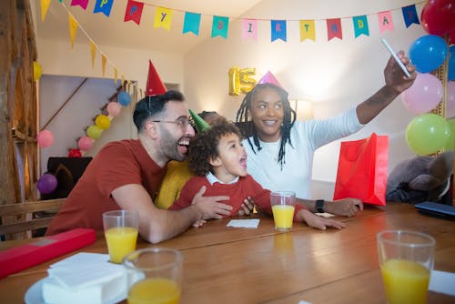 Free A Family with Party Hats Taking a Groupfie Stock Photo