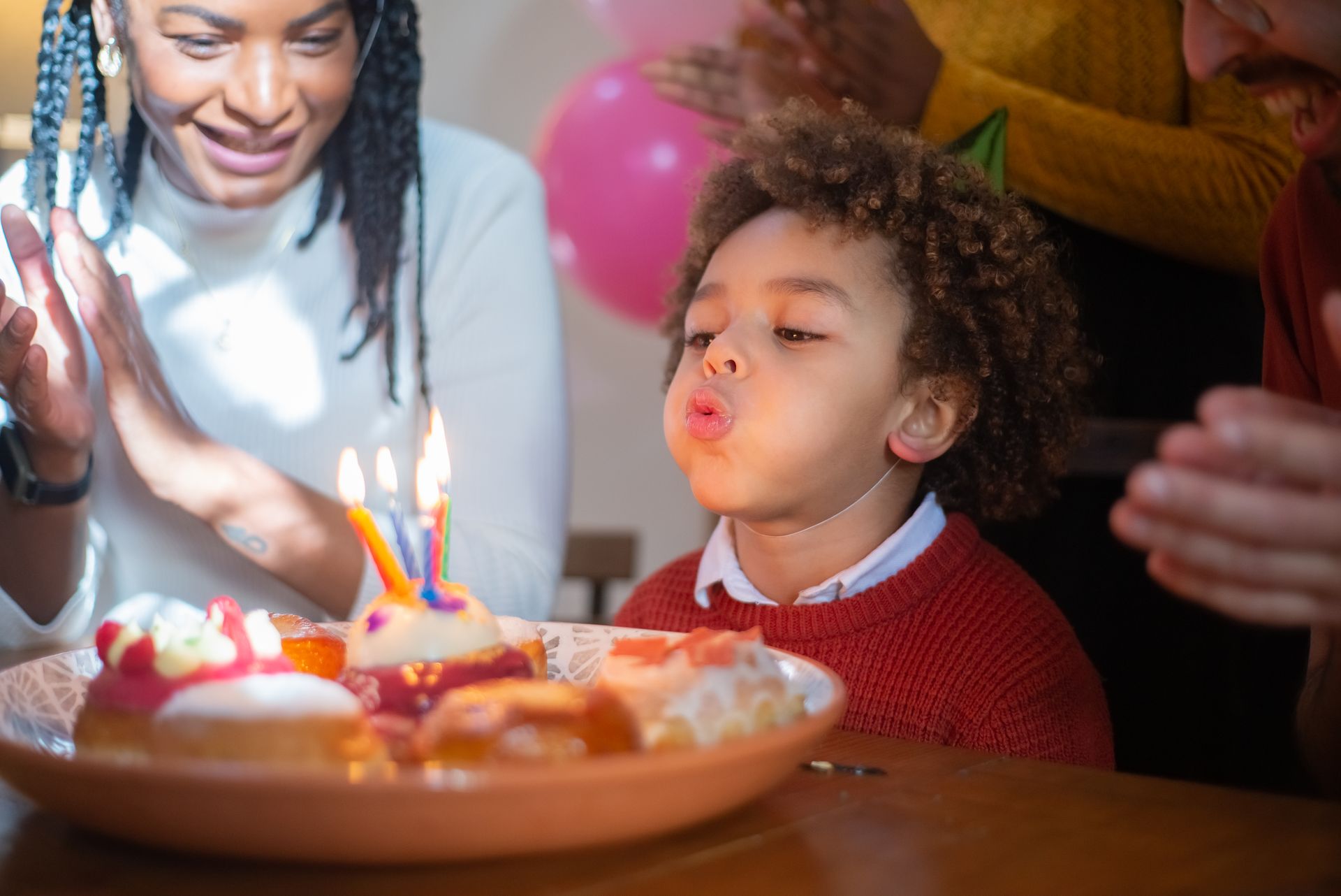 A joyful birthday celebration with a child blowing out candles surrounded by family, capturing a happy moment.