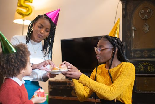 Family birthday party indoors with celebration hats and cake, fostering happiness and togetherness.