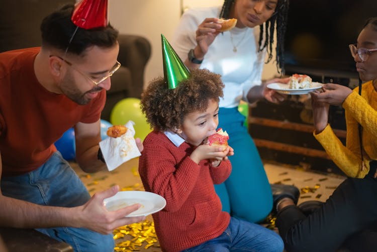 People Wearing Party Hats Busy Eating Donuts 