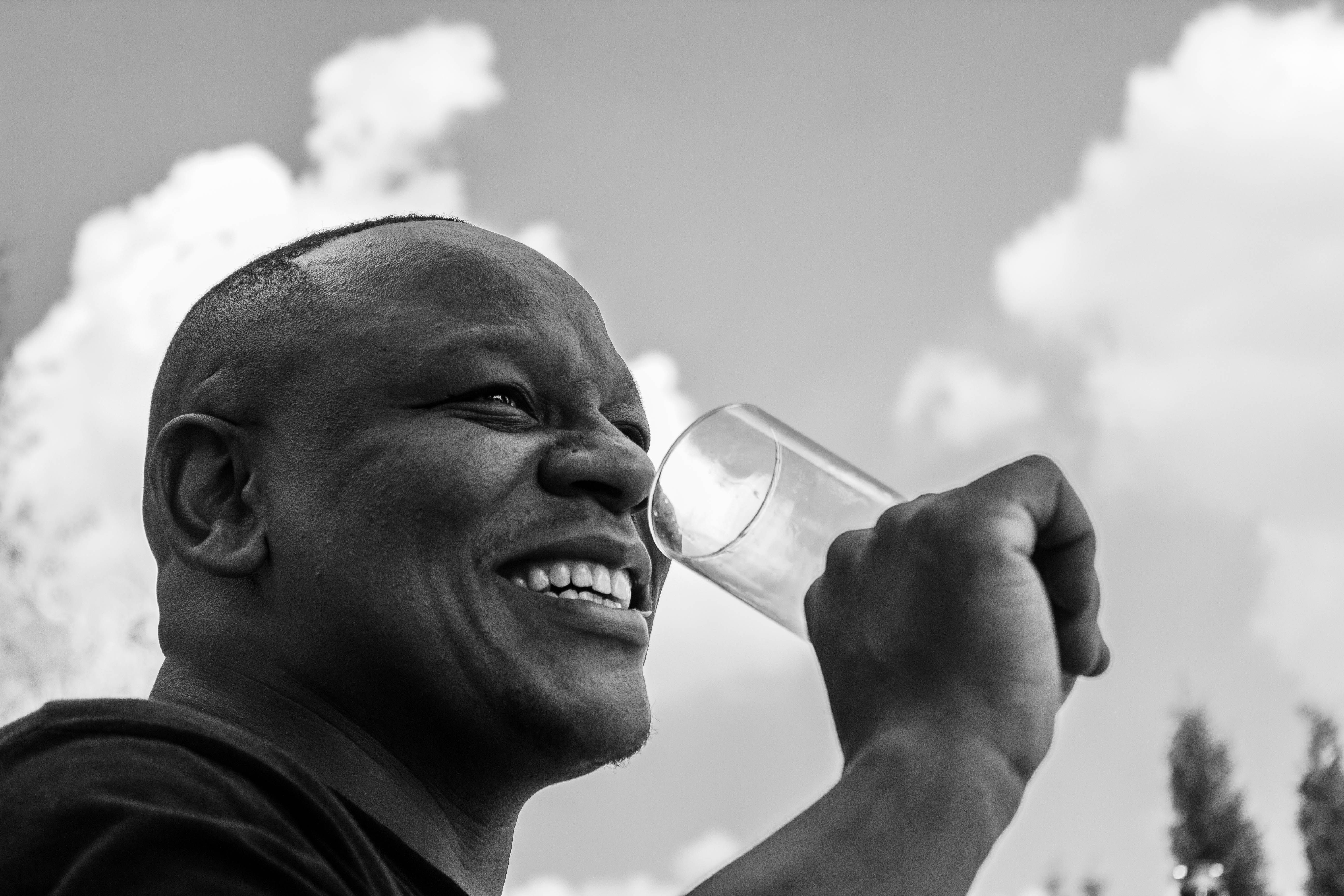 A person drinking a glass of water, looking refreshed and happy
