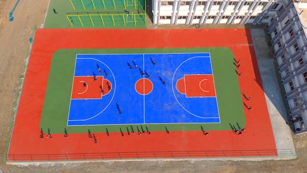 Aerial view of outdoor basketball court with players in Jamnagar, India.