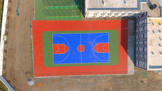 Aerial perspective of a vibrant outdoor basketball court in Jamnagar, India.