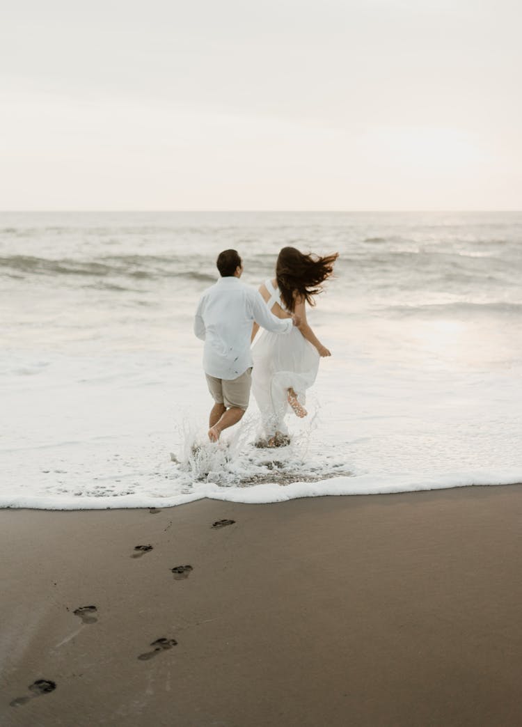 A Couple Running On A Beach