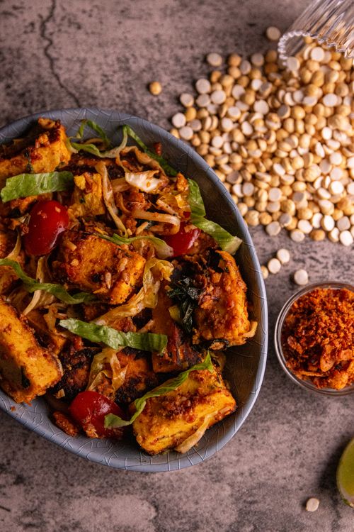 Tofu stir fry with cherry tomatoes and spices in a rustic bowl
