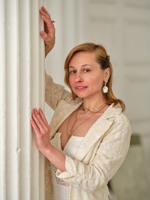 Free Elegant woman in white jacket leaning on column Stock Photo