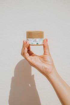 Hand holding eco-friendly skincare product, showcasing label design in natural lighting.
