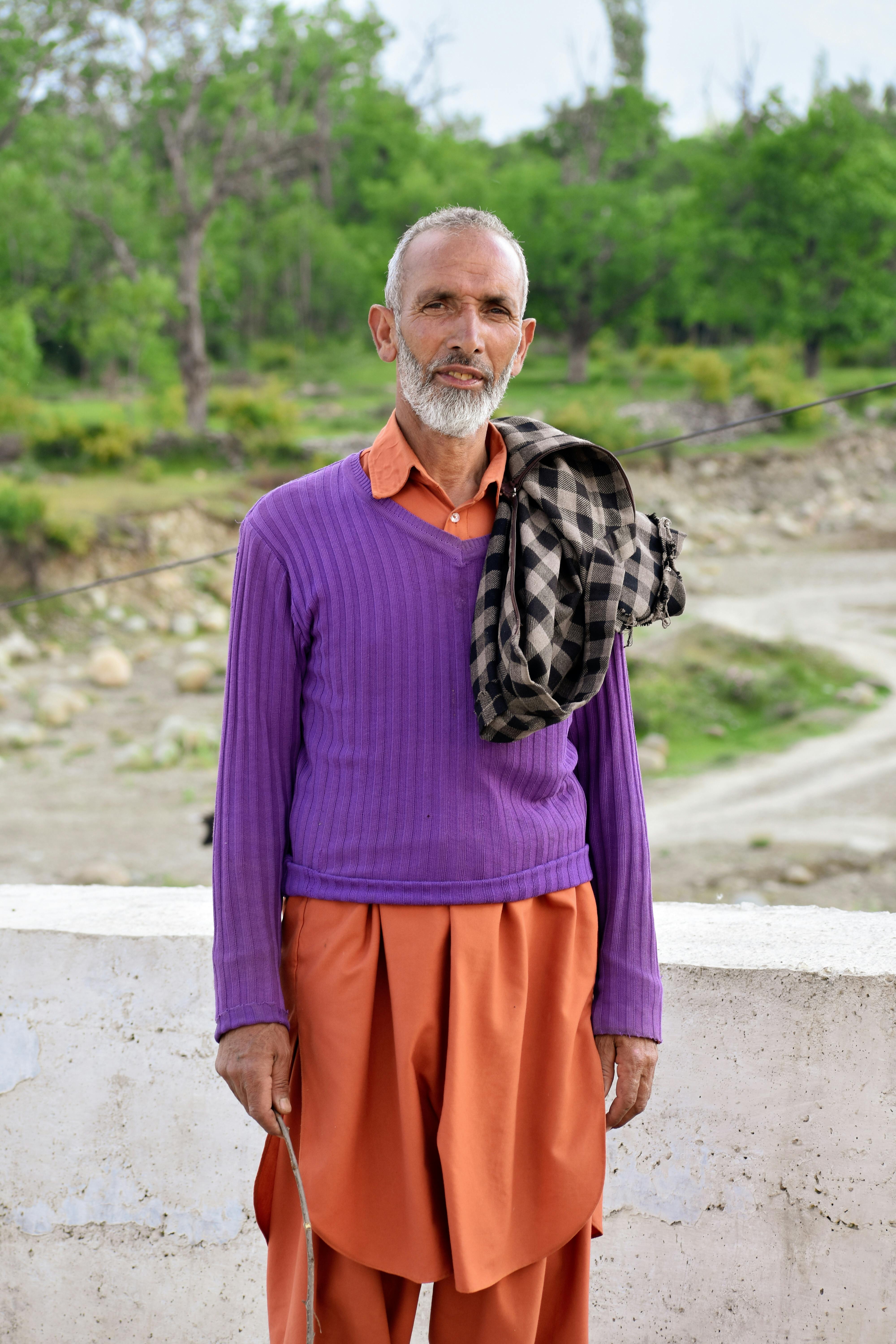 an elderly man in purple sweater standing