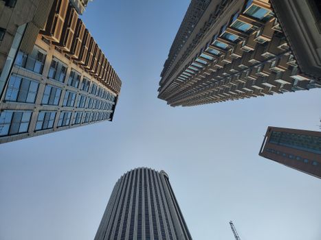 Dynamic perspective of towering skyscrapers under a clear blue sky, emphasizing modern architecture.