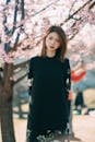 Gorgeous young ethnic woman standing near blooming cherry tree in park