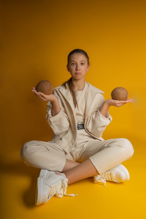 A Woman in Beige Jacket Holding Coconuts