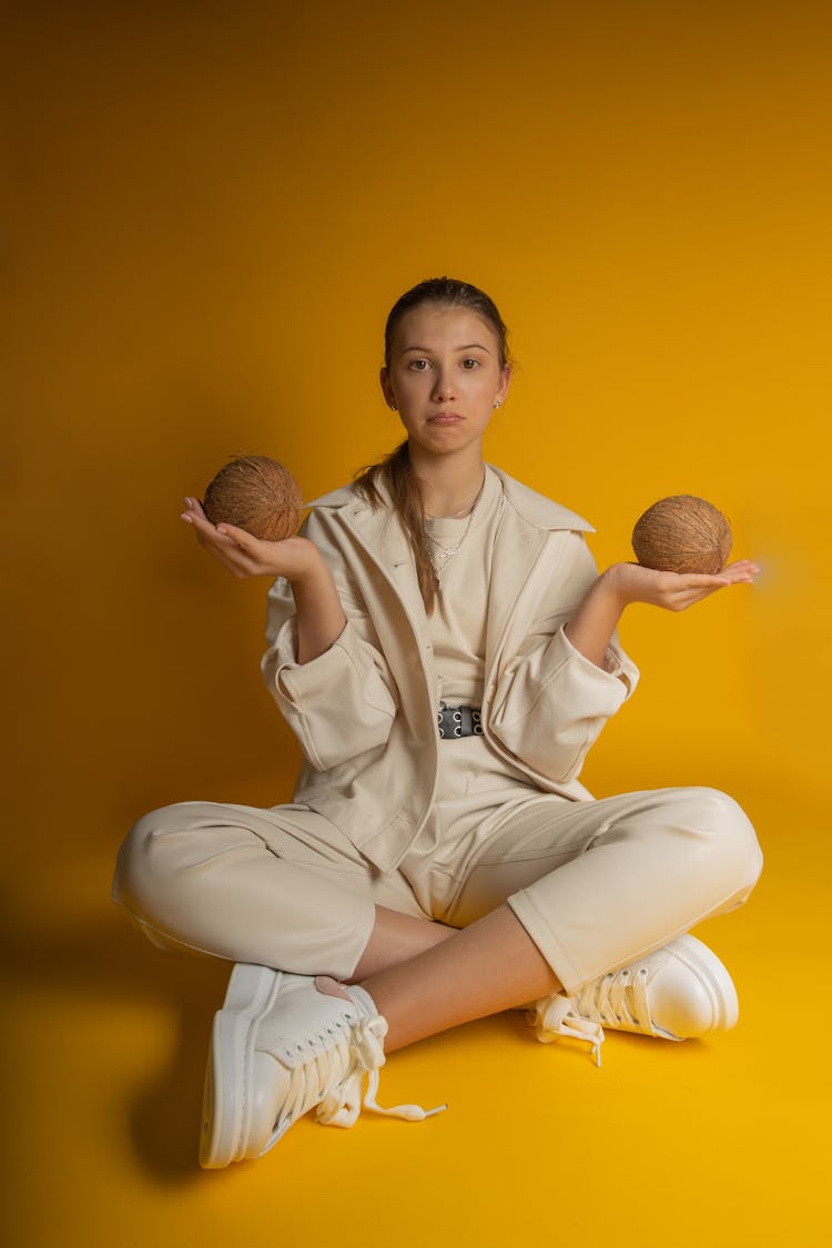 A Woman In Beige Jacket Holding Coconuts