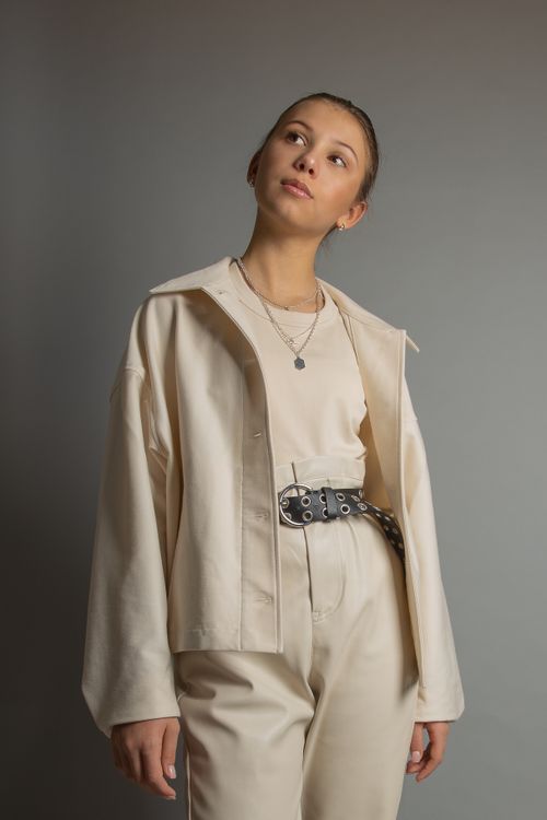 Free Portrait of a young woman wearing stylish clothing in a studio setting, showcasing modern fashion. Stock Photo
