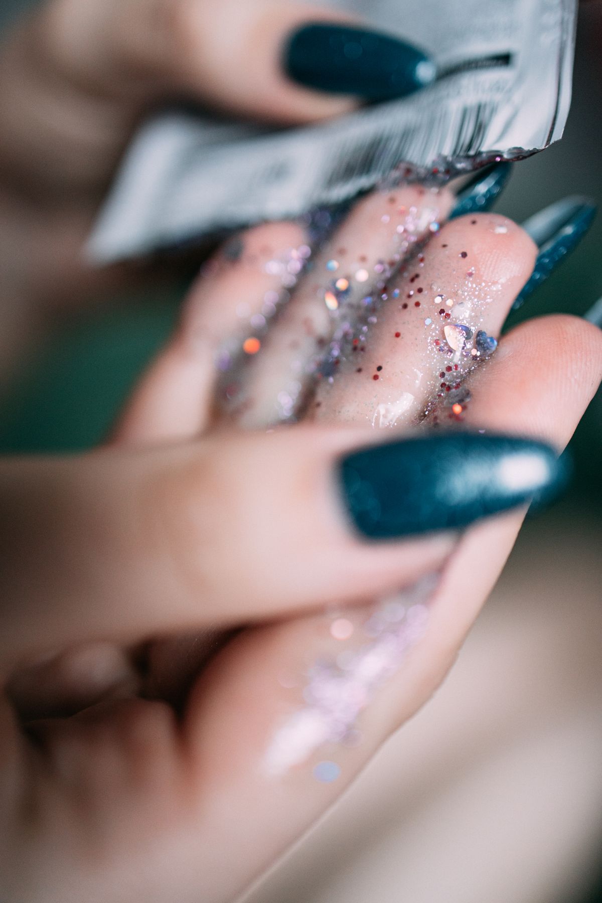 Detailed shot of a manicured hand with glitters, showcasing beauty and skincare elements.