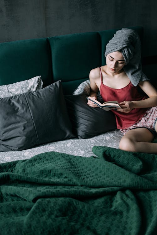 Free A Woman Reading a Book on a Bed  Stock Photo