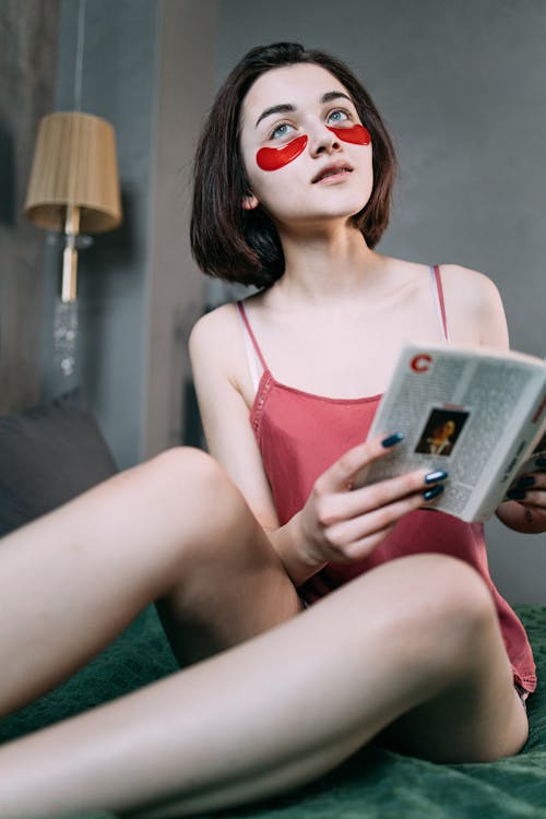 Free Woman with Red Eye Patches Reading Book Stock Photo