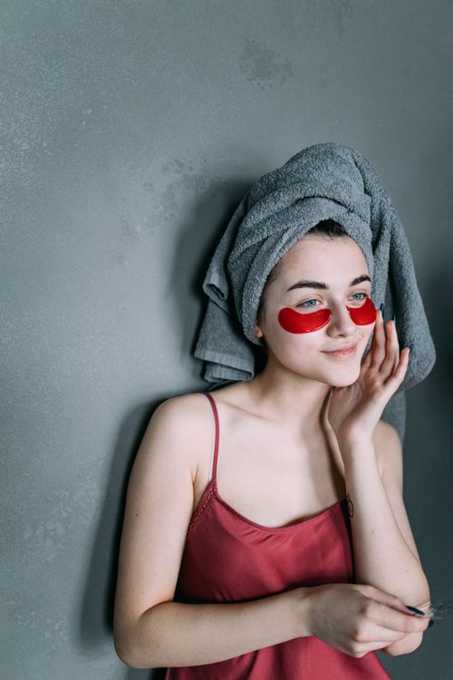 Free A young woman enjoying a home spa treatment, applying eye patches for skincare and relaxation. Stock Photo