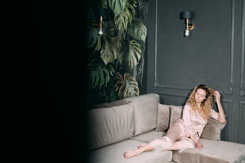 Free Woman Wearing Silk Sleepwear Sitting on the Gray Sofa  Stock Photo