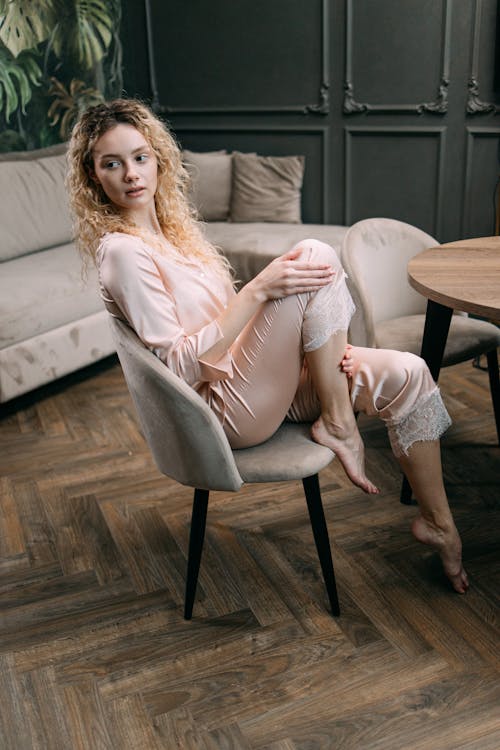 Woman in Pink Sleepwear Sitting on Beige Chair