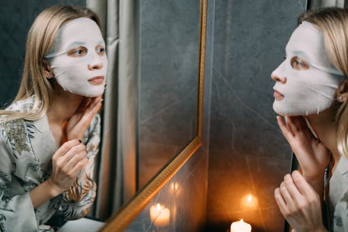 A Woman With Sheet Mask Looking at the Mirror 