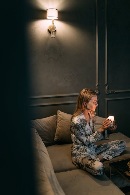 A Woman in a Pajama Holding a Burning Candle