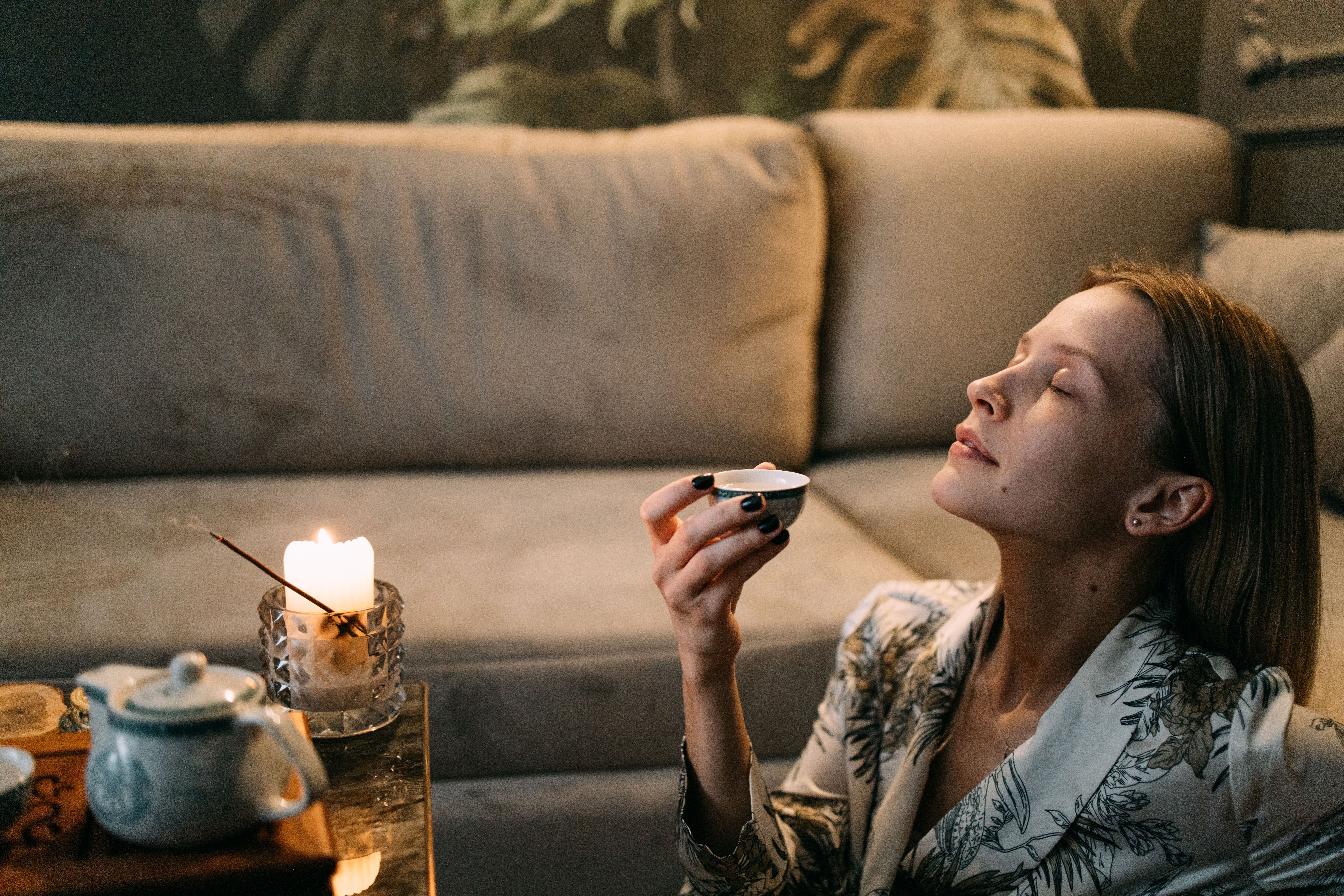 Woman enjoying a calming tea ritual at home with candlelight for anxiety relief
