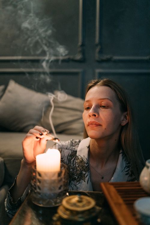 Free A woman lights a candle in a calm indoor setting, exuding relaxation and tranquility. Stock Photo
