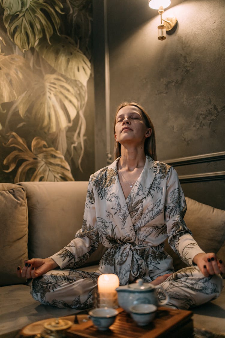 A Woman Sitting On The Couch While Meditating