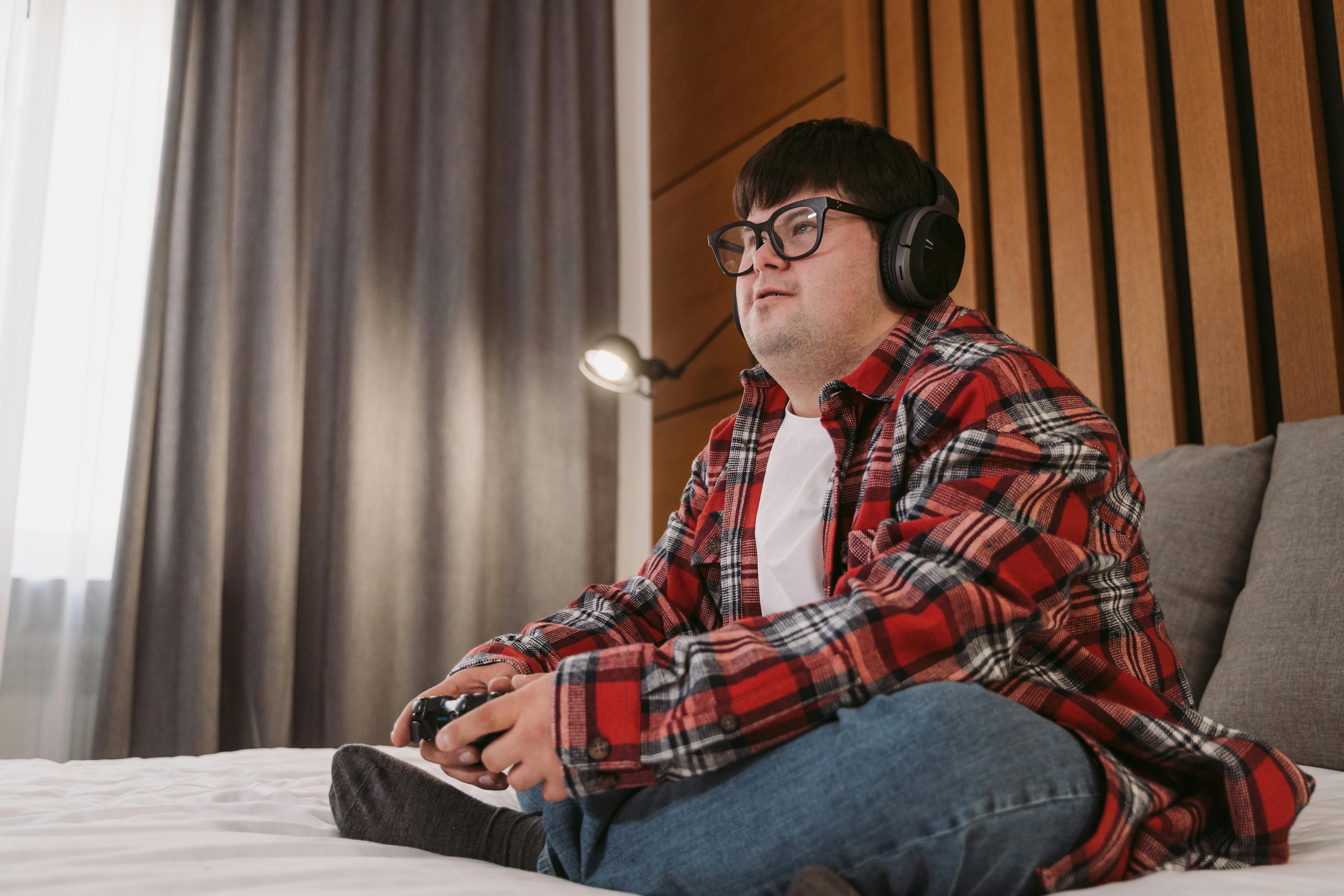 man in red white and black plaid dress shirt and blue denim jeans sitting on bed