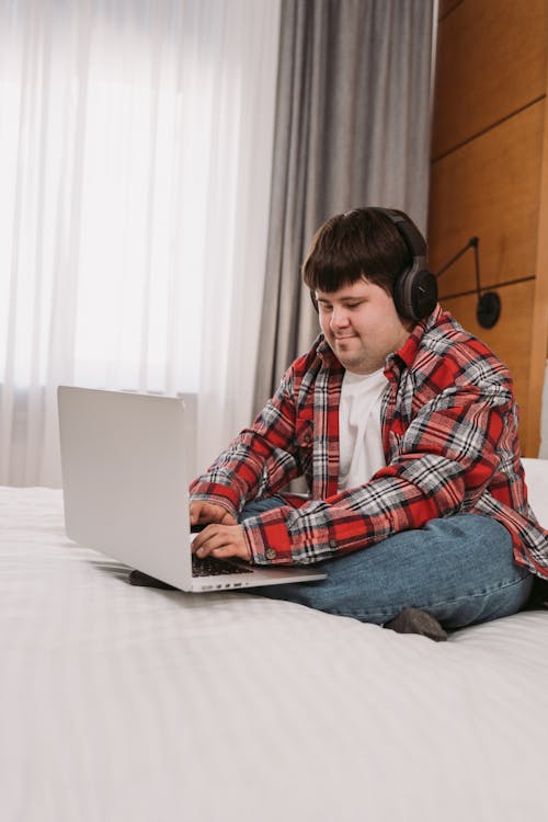 A Man in Plaid Long Sleeves Typing on His Laptop