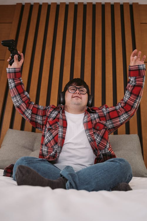 A Man in Plaid Long Sleeves Sitting on the Bed