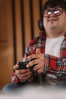 Man wearing headphones and plaid shirt enjoying a video game with a wireless controller.