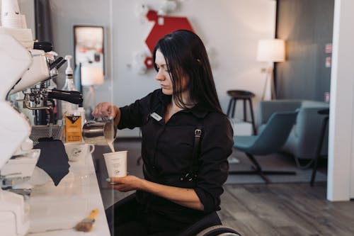 Free A Woman in Black Long Sleeves Pouring Milk on a Paper Cup Stock Photo