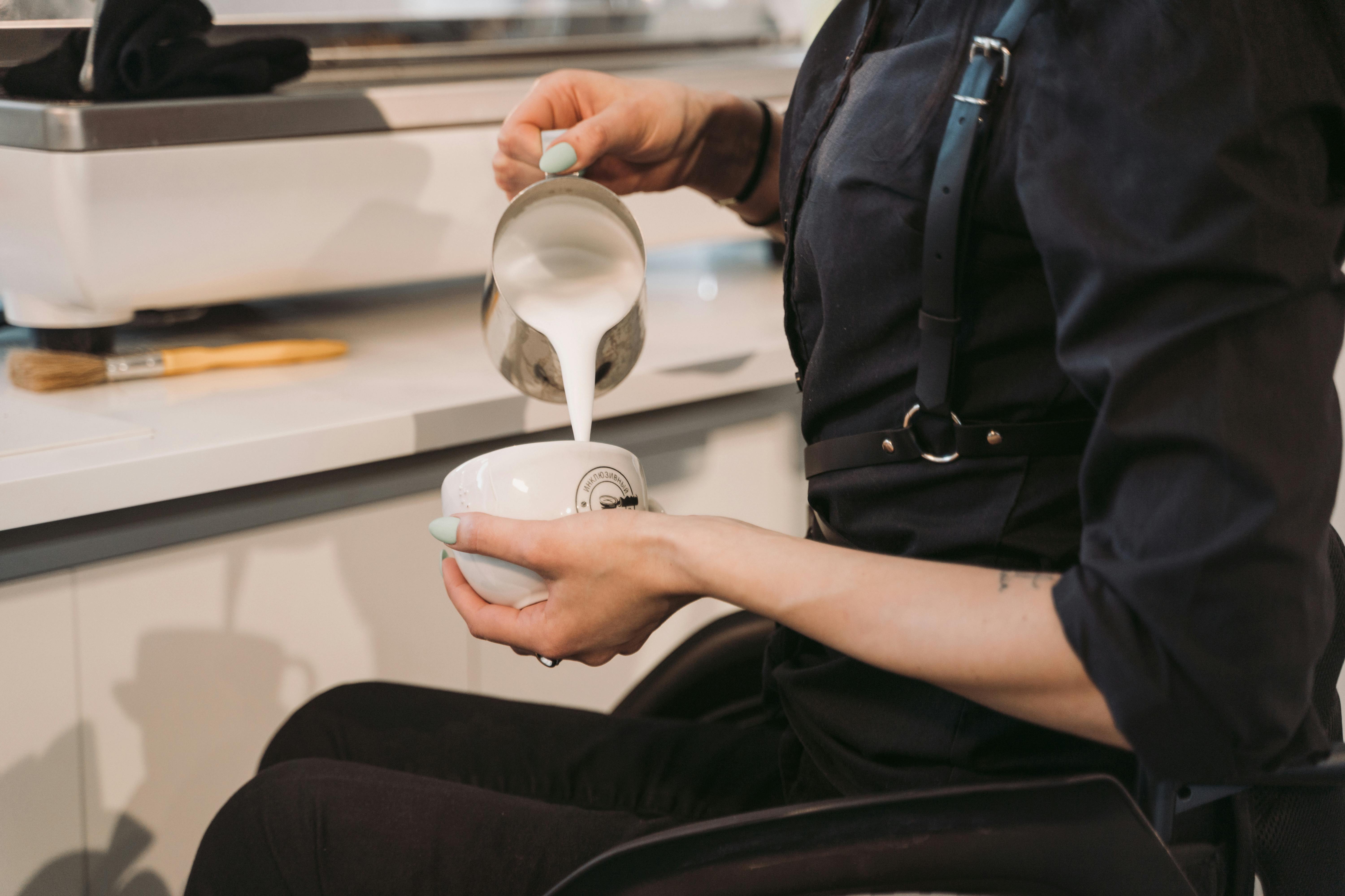 person in black button up shirt holding white ceramic mug