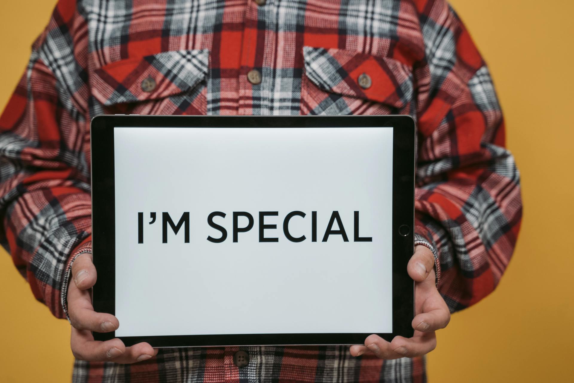 A Person in Red and White Plaid Long Sleeve Shirt Holding Digital Tablet with Text