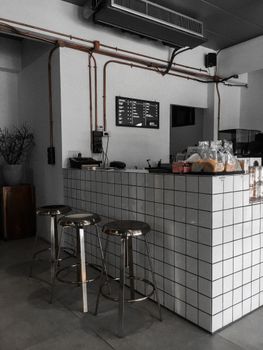 Stylish café interior showcasing a modern industrial design with white tiles and metal stools.