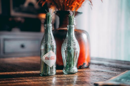 Glass Coca Cola bottles used as vases in a rustic decor setting on a wooden table.
