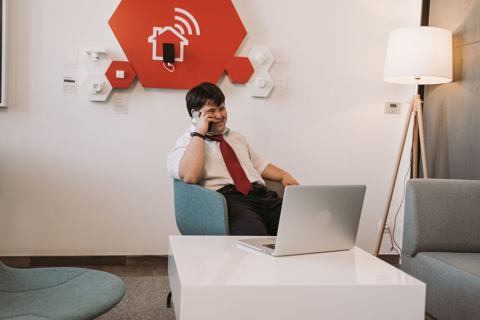 A professional with Down syndrome smiling while taking a work call beside a laptop