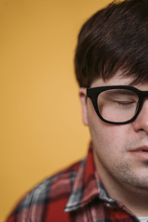 Free Half-face close-up of a man with eyeglasses against a yellow background. Stock Photo
