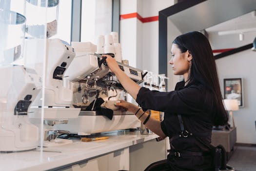 A barista expertly prepares coffee at an espresso machine inside a modern cafe.