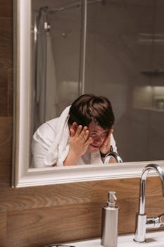 Adult man with Down syndrome washing face in bathroom mirror, promoting personal hygiene and wellness.
