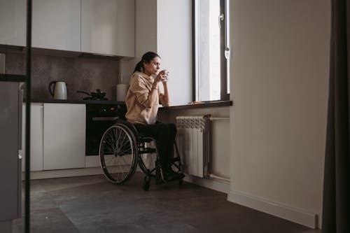 Woman Sitting on Wheelchair while Drinking Coffee
