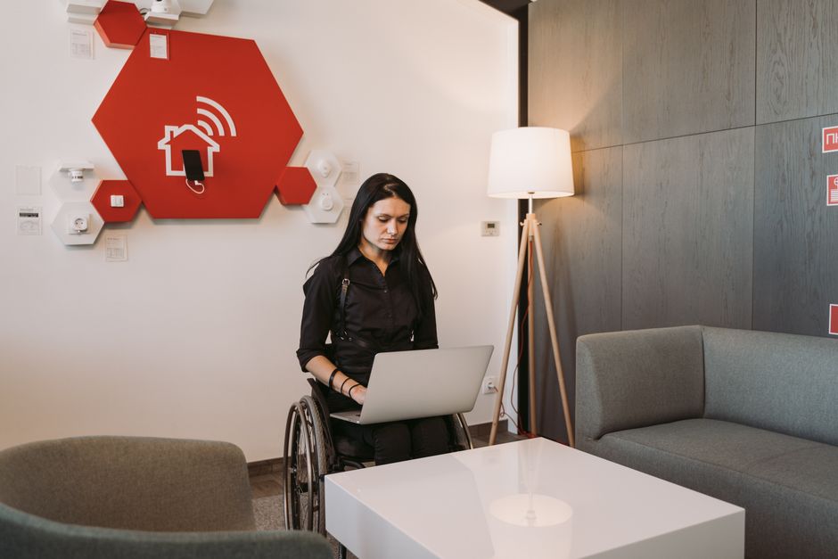 Una mujer en silla de ruedas usando un portátil en un entorno de oficina moderno, destacando la accesibilidad y la tecnología.