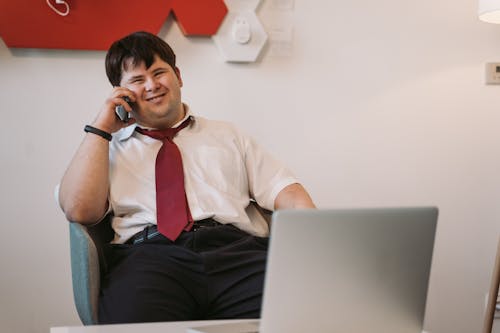 Free A Man Sitting on the Chair while Talking on the Phone Stock Photo