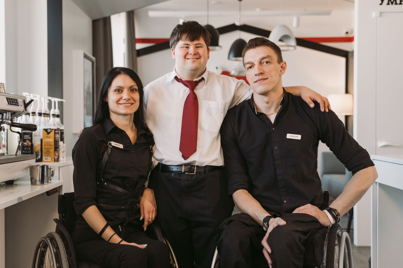 A diverse group of adults, including wheelchair users, smiling together in a community café