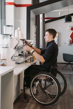Barista in a wheelchair making coffee at a modern café, showcasing accessibility.